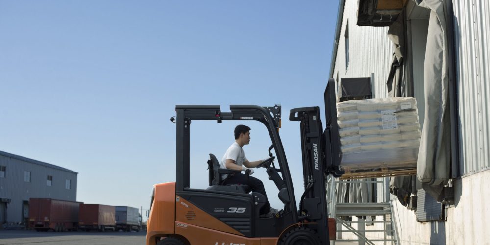 Worker with forklift in loading dock